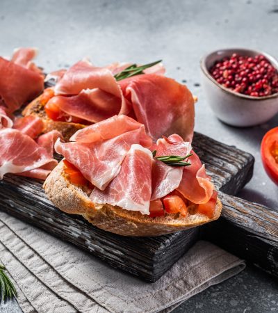 Spanish Tapas - Toast with tomatoes and cured Slices of jamon iberico ham on wooden board.